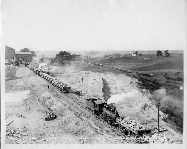 <p>Construction trains are shown loaded with rock going to the Crushing Plant located near the Grand Trunk Railway Bridge on the Welland Canal. Photo attribution: St. Catharines Museum - 1273-N</p>